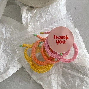 Détail d'élastiques à cheveux à volants jaunes, orange et roses dans un sac cadeau