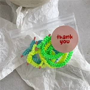 Détail de chouchous froncés aux couleurs néon vives dans un emballage cadeau transparent