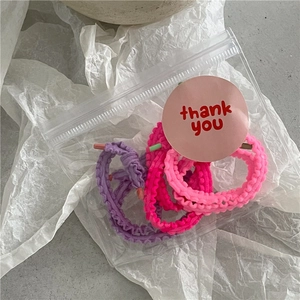 Gros plan sur des chouchous en tissu volanté violet et rose dans un sachet avec étiquette