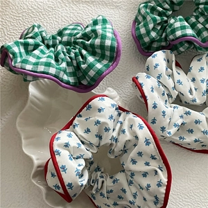 Détail de chouchous en tissu à carreaux verts et fleuris sur décor de coquillage