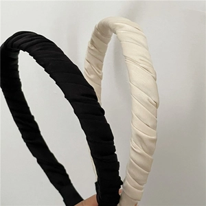 Détail de serre-têtes en tissu plissé noir et crème avec une texture douce et ridée
