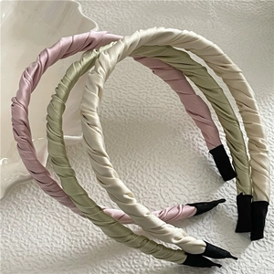 Trois serre-têtes en tissu plissé rose, vert et beige avec un design torsadé chic