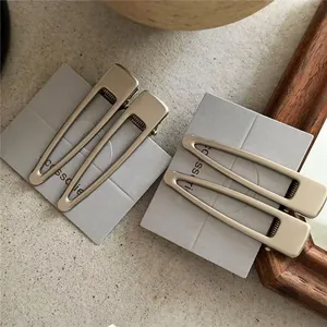 Set of 4 matte gold geometric hair clips with rectangular wavy edges on display card