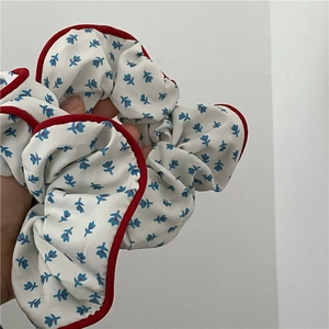 Chouchou fleuri en tissu bleu avec bordure passepoilée rouge vif contrastante
