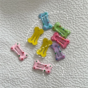 Détail de mini barrettes à cheveux en forme d'os avec pois aux couleurs crème macaron