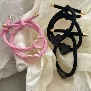 Pink and black twill knotted hair ties with metallic gold caps and heart charms