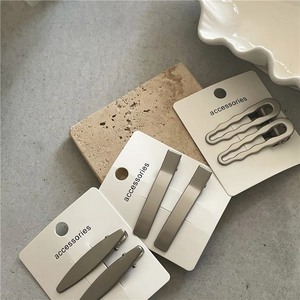 Detail of matte silver metal hair clips in geometric shapes on display cards