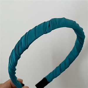 Vue détaillée de la texture du tissu satiné froncé et du bandeau plissé bleu paon