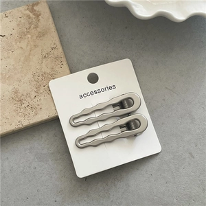 Detailed view of two silver wavy wave metal hair clips on accessory display card