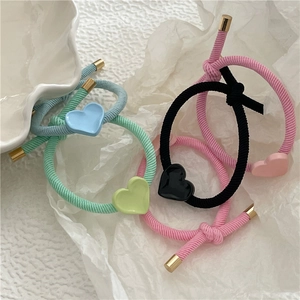 Close-up of colorful twill knotted hair ties with glossy gold heart-shaped charms