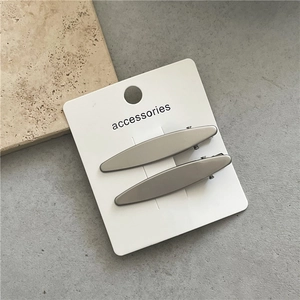 Close-up of minimalist matte grey metal hair clips set on a stone background