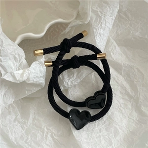 Close-up of black elastic hair ties with golden metal ends and shiny heart-shaped charms