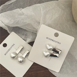 Detail of silver hair clips with round and heart-shaped faux pearls on packaging