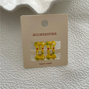 Détails de barrettes jaunes en forme d'os avec pois colorés sur carte d'accessoires