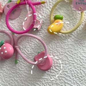 Detail of colorful fruit-themed hair ties with strawberry and mango resin charms