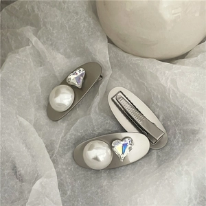 Detail view of silver matte hair clips with large faux pearls and heart shaped crystals