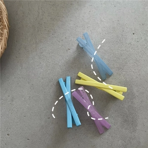 Détail de quatre pinces à cheveux mates aux tons pastel bleu, jaune et violet