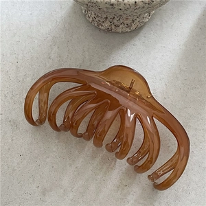 Macro detail of amber jelly hair claw clip with golden metal spring and polished finish