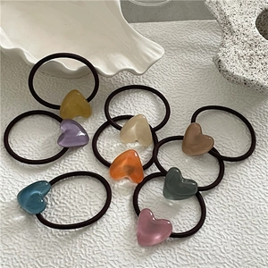 Close-up of colorful heart hair ties with elastic ropes on a white shell plate