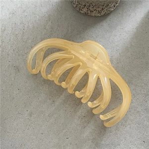 Macro shot of large amber jelly hair claw clip with multi-tooth design on stone texture