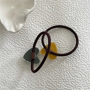 Close-up of yellow and dark gray acrylic heart charms on coffee-colored elastic hair bands