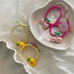 Close-up of cute strawberry and lemon resin charms on colorful elastic hair bands