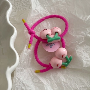Detail of two pink cherry elastic hair ties on a minimalist white textured background
