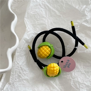 Close-up of dual black elastic hair ties featuring cute yellow corn resin charms