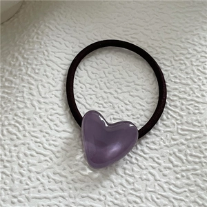 Close-up of heart hair tie featuring a purple resin heart charm on black elastic band