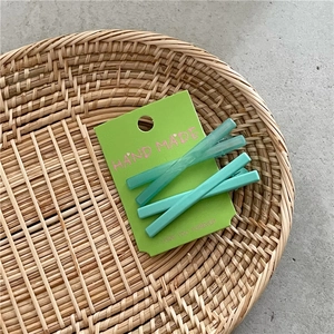 Détail de deux pinces à cheveux vert mat sur une carte dans un plateau tressé