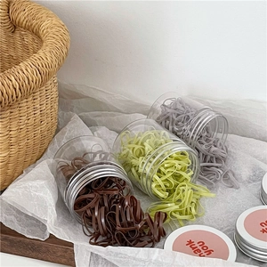 Macro detail of three colorful elastic hair band sets in transparent jars with silver lids