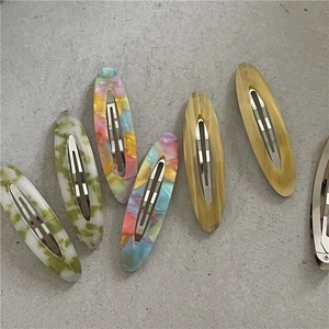 Detailed view of oval acetate hair clips with marble patterns and metal spring clips