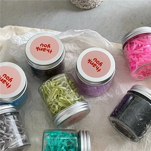 Overhead view of colorful elastic hair bands in clear jars with thank you labels