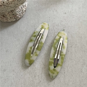 Detail of green and white marble acetate hair clips with silver metal buckles