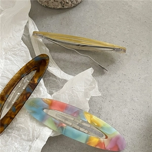 Macro detail of tortoiseshell and watercolor acetate hair clips with handmade engraving