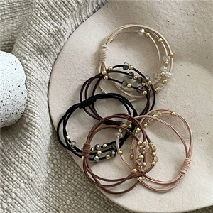 Élastiques à cheveux perlés avec strass et perles dorées sur plateau céramique