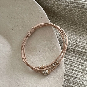 Détail d'un élastique rose avec perles en strass doré sur une assiette en céramique