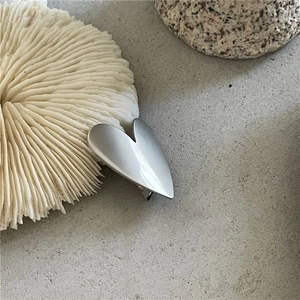 Fermaglio per capelli a cuore in lega d'argento minimalista con finitura opaca su sfondo neutro