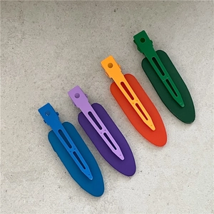 Macro detail of four colorful matte oval hair clips arranged on a grey texture