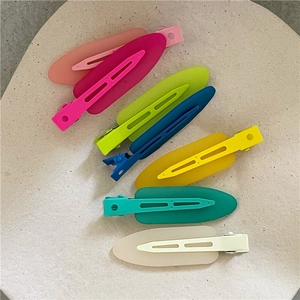 Macro detail of six colorful jelly-textured waterdrop hair clips on a beige tray