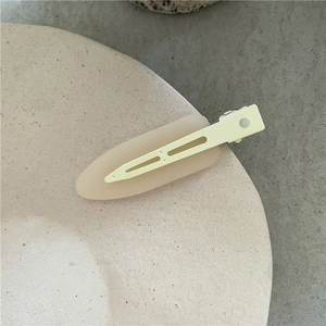 Close-up of minimalist apricot jelly teardrop hair clip on a neutral stone background