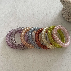 Lot de 7 chouchous spirales translucides en couleurs variées sur une surface en pierre