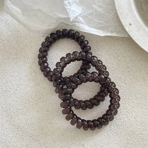 Vue détaillée de trois élastiques spirale marron café sur fond à texture de pierre