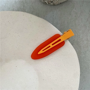 Close-up of orange jelly texture drop clip with yellow metal duckbill on ceramic tray
