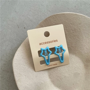 Close-up of a pair of bright blue star-shaped metal hair clips on display card