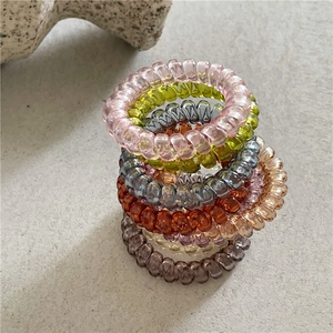 Détail macro d'élastiques à cheveux spirales translucides multicolores sur surface en pierre