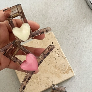 Brown acrylic heart hair claw clips in cream and pink colors on a stone tray