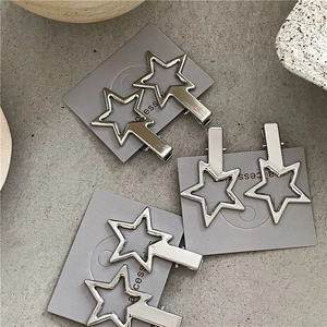 Barrettes étoile Y2K en argent au design évidé sur carte sur fond de texture ciment