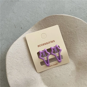 Detail view of two purple star hair clips on a beige display card and ceramic tray