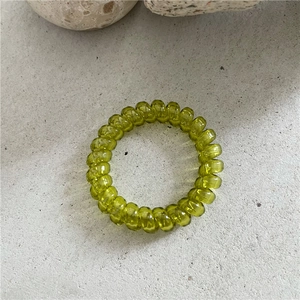 Détail macro d'un élastique spirale vert olive translucide sur une surface en pierre